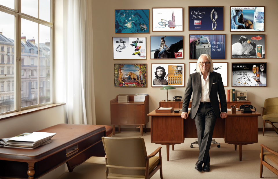 Roland Anstett dans un bureau entouré d’affiches publicitaires